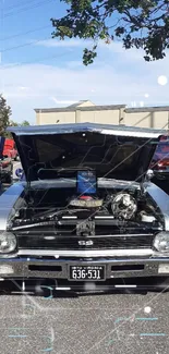 Front view of a classic car with open hood under a clear sky.