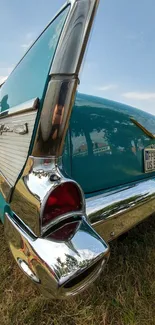 Teal vintage car with chrome detailing on grass.