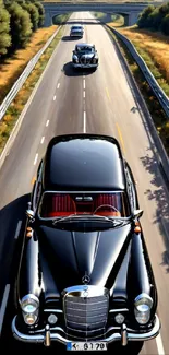 Black classic cars on an open highway under clear skies.