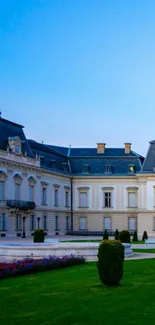 Elegant European palace with lush garden and blue sky background.