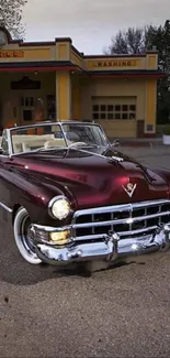 Maroon classic convertible parked at vintage gas station.