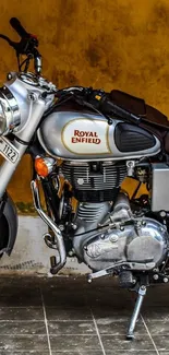 Classic Royal Enfield motorcycle in front of a rustic, orange wall.