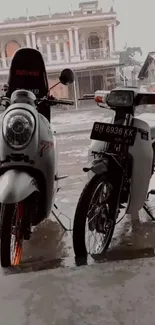 Two classic motorcycles parked in rain with vintage background.