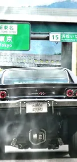 Rear view of classic black muscle car on highway with Tokyo signs.