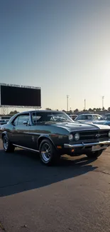 Classic car parked at drive-in during sunset.