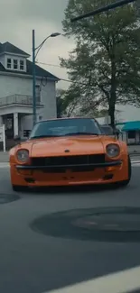 Classic orange car driving on an urban street, perfect for mobile wallpapers.