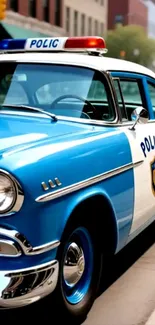 Vintage blue and white police car parked on city street.