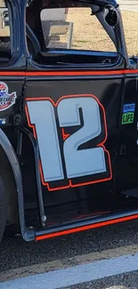 Vintage racing car with number 12, black and orange design in the foreground.