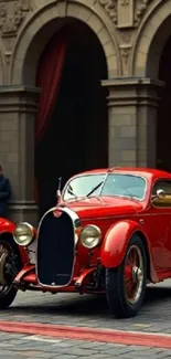 Classic red vintage car in historic town setting.