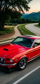 Classic red car on a scenic road with mountains.