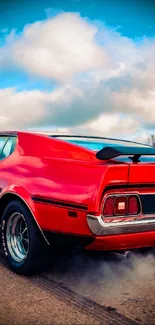 Vibrant red muscle car on open road under clear sky.