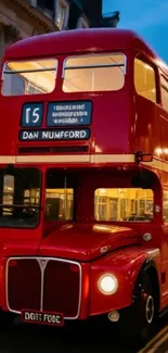Red double-decker bus at night in London.