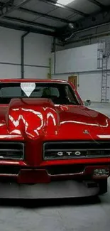 A classic red GTO muscle car parked in a garage setting.