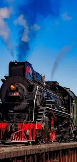 Steam train crossing a bridge under a clear blue sky with vibrant scenery.