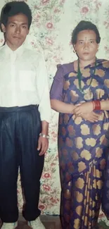 Vintage portrait of a man and woman in traditional attire with a floral background.