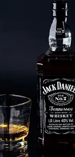 Whiskey bottle with glass on dark background.