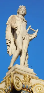 Classical marble statue against a clear blue sky.