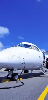 Small aircraft ready for boarding against a bright blue sky on the runway.