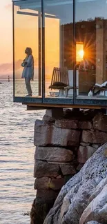 Glass room overlooking sunset on a cliff by the ocean.