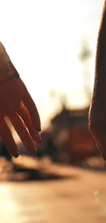 Two hands reaching in a sunset-lit urban setting, creating an intimate moment.