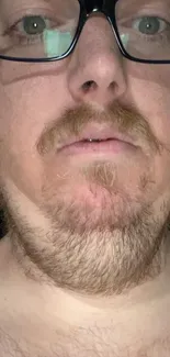 Close-up portrait of a man's face with glasses and facial hair.