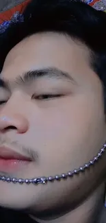 Close-up of face with beaded chain over colorful background.