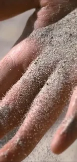 Close-up of a hand covered in sand, showcasing texture and natural tones.