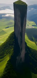 Vertical mountain and green fields with misty clouds in a scenic landscape.