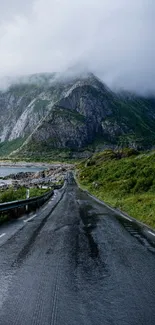 Misty mountain road with lush greenery and moody clouds.