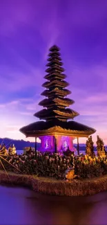 Balinese temple silhouetted against a vibrant purple sunset.