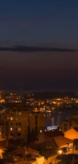 Night view of a coastal city with illuminated buildings and a dark sky.