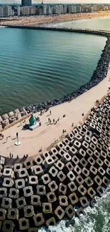 Aerial view of coastal city breakwater path with skyline.