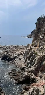 Scenic view of rocky cliffs beside a tranquil blue ocean under a clear sky.