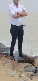 Man standing on rocks by a calm seashore.