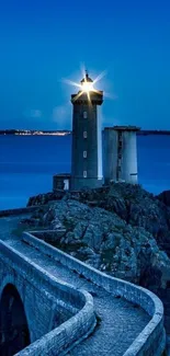 Lighthouse on rocky coast under a starry night sky with deep blue hues.