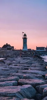 Lighthouse on a rocky pier at sunset with vibrant pink sky.