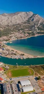 Aerial view of coastal town with mountains and blue sea in a serene mobile wallpaper.