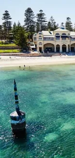 A coastal scene with turquoise waters and paddleboarders near a beachfront building.