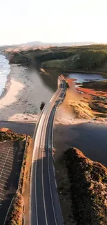 Aerial view of a coastal road at sunset with ocean and mountains.