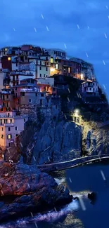 Coastal village illuminated at night with vibrant lights against a deep blue sky.