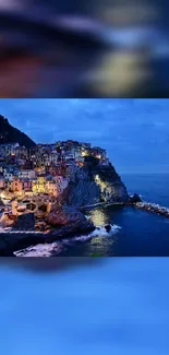 Night view of a lit coastal village by the sea with vibrant blue hues.