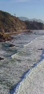 Aerial view of ocean waves crashing on a rocky coast under a blue sky.