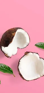 Coconut halves on pink background with green leaves.