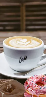 Coffee cup with latte art and colorful donuts on wooden table.