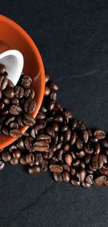 Coffee beans spilling on dark slate background.