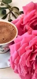 Cup of coffee next to vibrant pink roses.