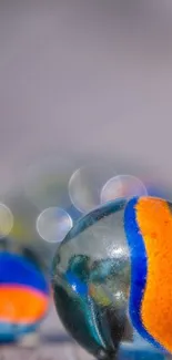 Close-up image of colorful marbles with orange and blue patterns on a light gray background.