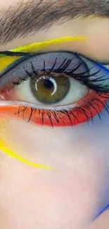 Close-up of an eye with artistic colorful paint streaks on skin.