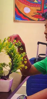 Young person with plant and colorful art on the wall.