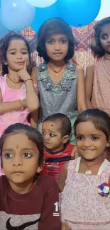 Kids smiling with colorful balloons at a celebration event.